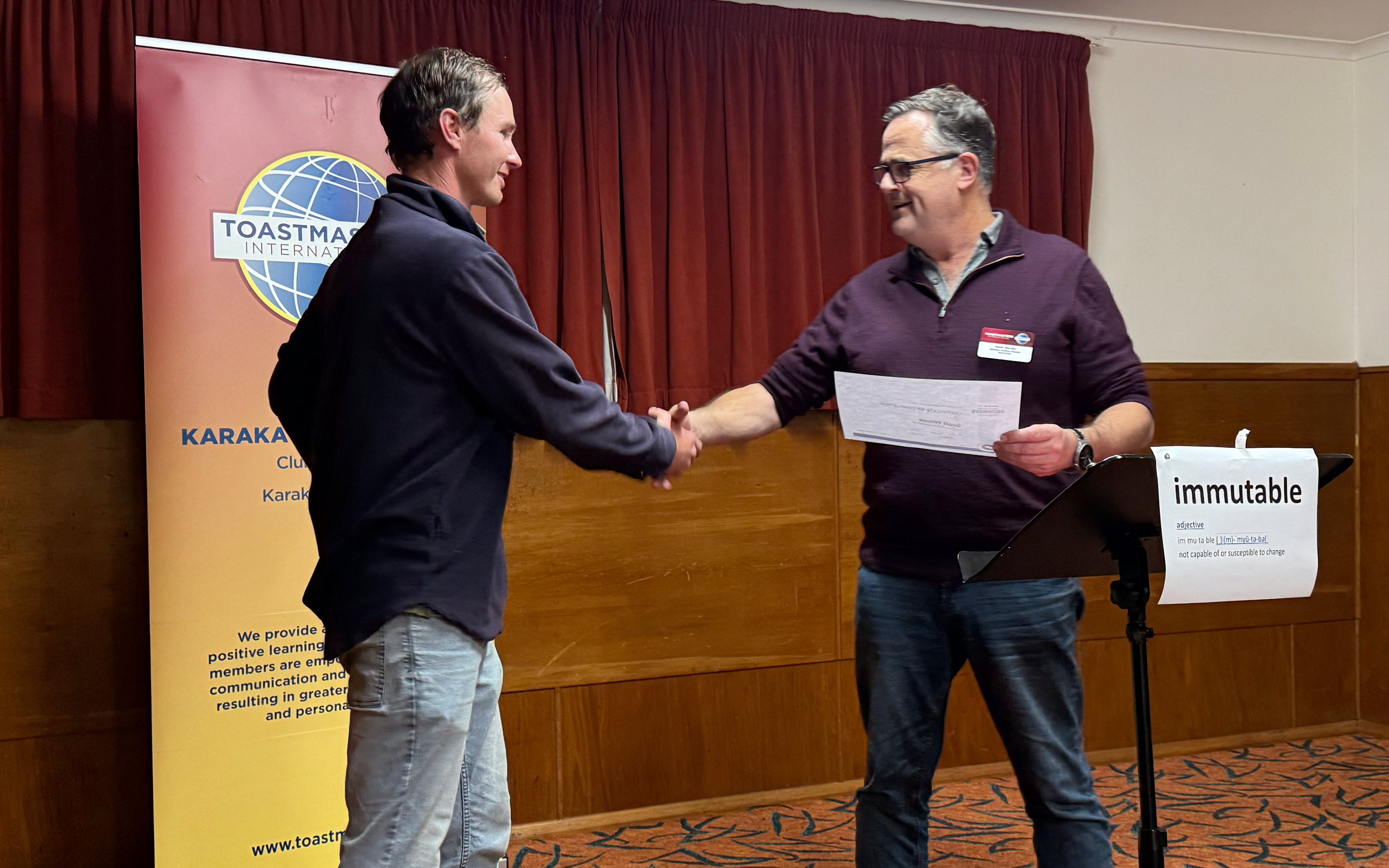Member receiving an award handshake on stage